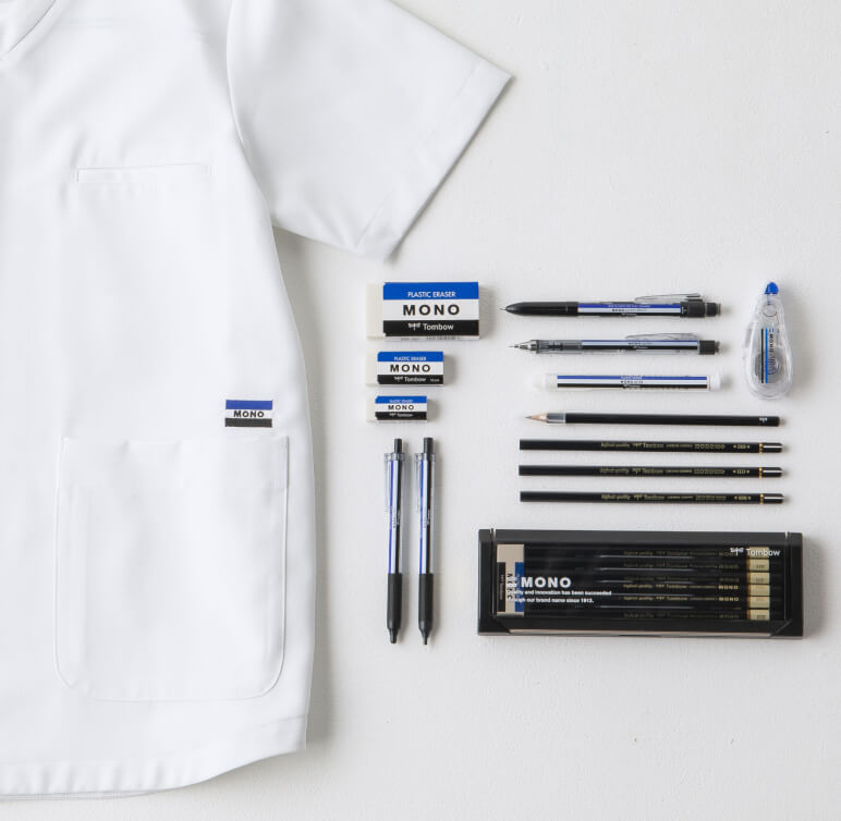 トンボ鉛筆「MONO」シリーズの文具と医療ウェアブランド「クラシコ」がコラボレーションしたスクラブ白衣が並んでいる様子